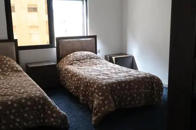 a hotel room with two beds and a window at شقق الاستقلال in Amman