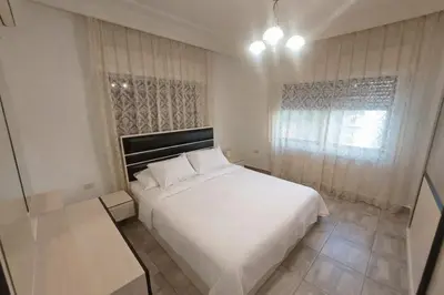 a bedroom with a white bed and a window at Wadi Saqra Family Apartment in Amman