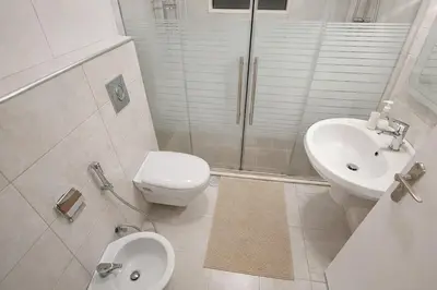a bathroom with a toilet and a sink and a shower at Wadi Saqra Family Apartment in Amman
