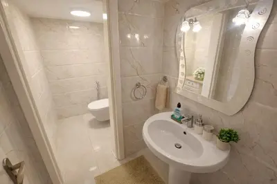 a white bathroom with a sink and a mirror at Wadi Saqra Family Apartment in Amman