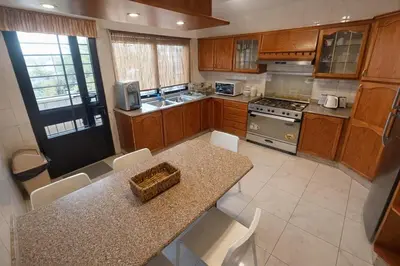 a kitchen with wooden cabinets and a table with chairs at Wadi Saqra Family Apartment in Amman
