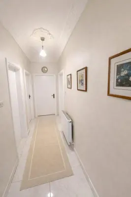 a hallway with white walls and a hallway with a radiator at Wadi Saqra Family Apartment in Amman