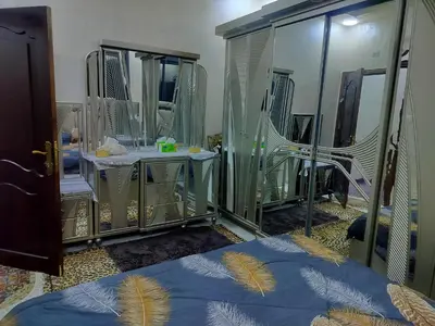 a bedroom with mirrors and a bed with blue sheets at شقق مفروشه فاخره2 in Aqaba