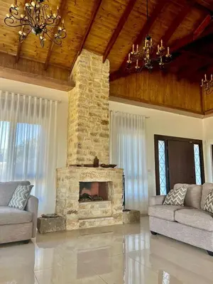 a living room with a stone fireplace in a house at Bait Ajloun in Khirbat Shīn