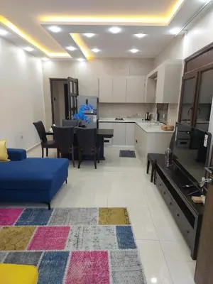 a living room with a blue couch and a kitchen at Bait Ajloun بيت عجلون 2 in Khirbat Shīn