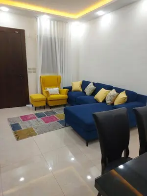 a living room with a blue couch and yellow chairs at Bait Ajloun بيت عجلون 2 in Khirbat Shīn