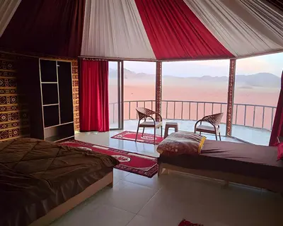 a bedroom with two beds and a balcony with a view of the desert at Teraa rum luxury camp in Wadi Rum