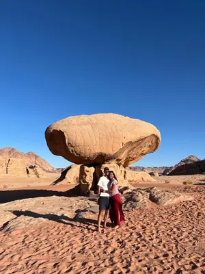 two people standing in front of a large rock at Wadi Rum Star Sky in Wadi Rum