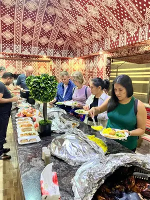 a group of people eating food at a buffet at Wadi Rum Star Sky in Wadi Rum