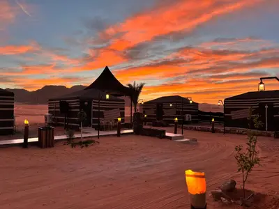 a sunset in the desert with buildings in the sand at Wadi Rum Star Sky in Wadi Rum