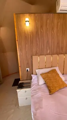 a bedroom with a bed with a wooden head board at Fortuna Rum Bubble Hotel & Jeep Tours in Wadi Rum