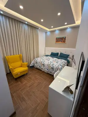 a bedroom with a bed and a yellow chair at شقة مميزة في عبدون -Special apartment in Abdon in Amman