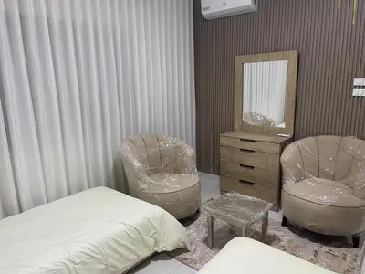 a bedroom with a bed and two chairs and a mirror at apartement khaled in Madaba