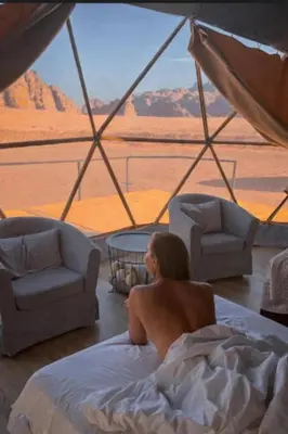 a woman laying in bed looking out at the desert at The Heritage Inn in Disah