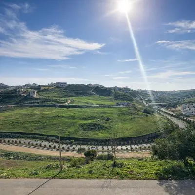 a view of a green field with the sun in the sky at Abdoun Elite Residence Stunning View in Amman