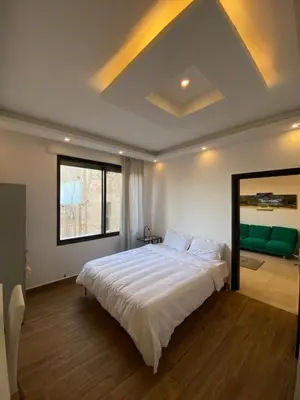 a bedroom with a large bed and a large window at Cozy Wabida in Amman