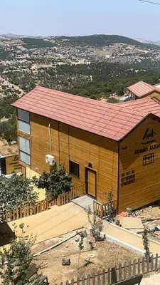 a large wooden building with a red roof at Akwakh Al-Kanz Huts Ajloun Jor in Ajloun