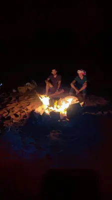 a group of three people sitting around a fire at Wadi Rum, Mars Cave in Wadi Rum