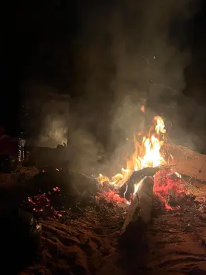 a fire is burning in the sand at night at Wadi Rum, Mars Cave in Wadi Rum