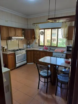a kitchen with wooden cabinets and a table and chairs at Cozy 3 bed-2 bath furnished apartment in Amman
