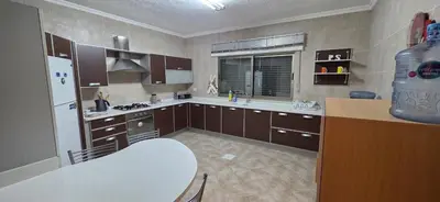 a kitchen with brown cabinets and a white refrigerator at شقة مفروشة فاخرة in Amman