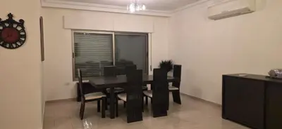 a dining room with a table and chairs and a clock at شقة مفروشة فاخرة in Amman