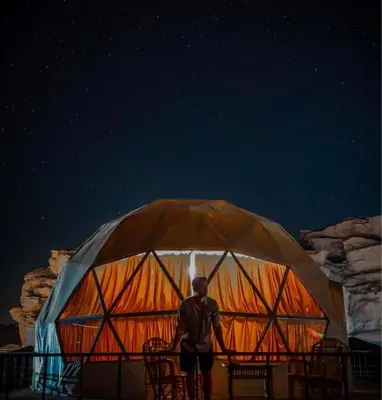 a man standing in front of a yurt at night at Silent Dunes Camp in Disah