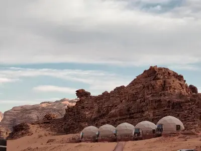 a group of domes in the desert next to a mountain at Silent Dunes Camp in Disah