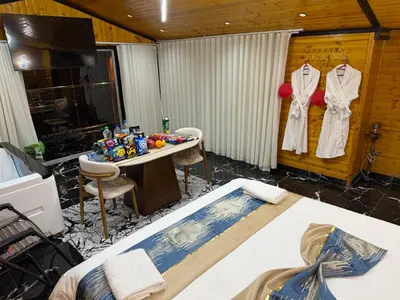 a room with a bed and a table with clothes hanging on a wall at Akwakh Al-Kanz اكواخ الكنز عجلون in Ajloun