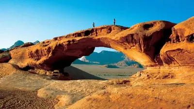 two people standing on top of an arch in the desert at Your Bedouin family home in Disah