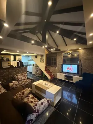 a living room with a large tv and a couch at City huts in Umm Uthainah