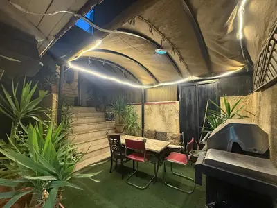 a room with a table and chairs and some plants at City huts in Umm Uthainah