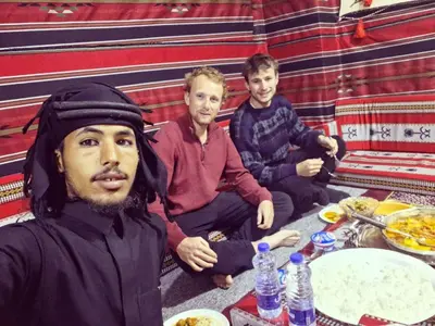 a group of three men sitting at a table with food at Salem Guesthouse Experience in Al Ḩayy