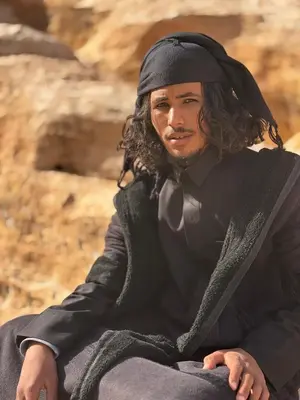a man with long hair sitting on the ground at Salem Guesthouse Experience in Al Ḩayy
