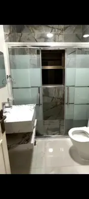 a bathroom with a shower and a sink and a toilet at Dair Ighbar Apartment