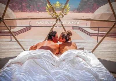 a man and a woman laying in a bed at WADI RUM BUBBLES lUXURY CAMP in Disah
