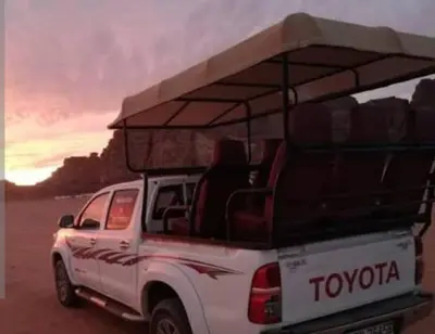 a white truck with a roof rack on the beach at Wadi Rum Nada Camp in Wadi Rum