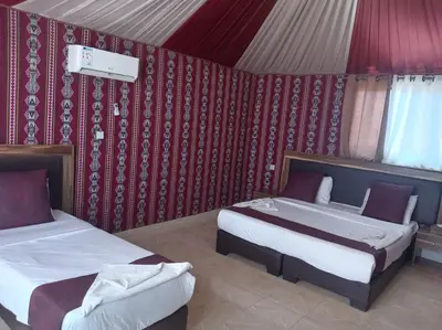 two beds in a room with red wallpaper at Wadi rum camp teem in Wadi Rum