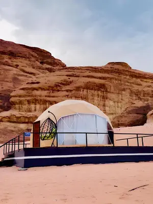 a tent on the beach next to a cliff at ULORA Luxury Camp in Wadi Rum