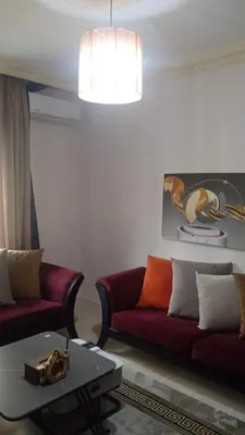 a living room with two red couches and a table at Studio at the heart of Jabl Amman in Amman