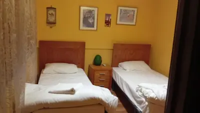 two beds in a room with yellow walls at Petra Neighbor Hostel in Wadi Musa