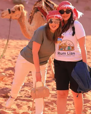 two women standing on the beach with a camel at Rum Lian Luxury Camp & Bubble Hotel in Disah