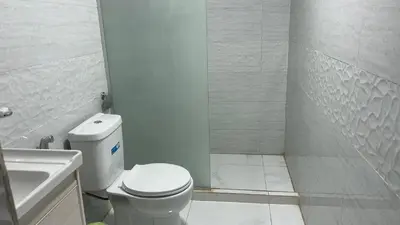 a white bathroom with a toilet and a shower at Wadi Rum -Lekshary Hamza 55 in Wadi Rum