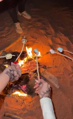a person with tattoos on their hands standing around a fire at Monte Carlos Luxury Camp in Disah