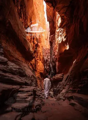 a man walking through a tunnel in a canyon at MAHA Rum Luxury Camp in Disah