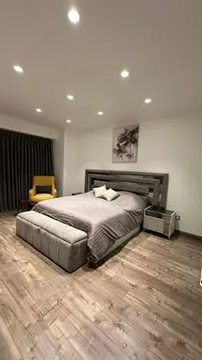 a bedroom with a large bed and a chair at Rashed's apartments at DAMAC Tower in Amman