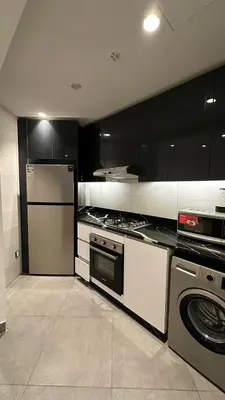 a kitchen with black and white cabinets and appliances at Rashed's apartments at DAMAC Tower in Amman