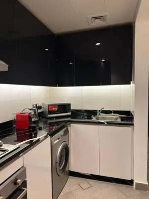 a kitchen with black cabinets and a washing machine at Rashed's apartments at DAMAC Tower in Amman