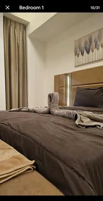 a bedroom with a large bed with a brown blanket at luxury apartments at DAMAC tower amman للعائلات برج داماك in Amman