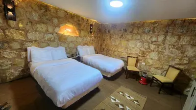 a bedroom with two beds and a stone wall at Petra Gateway Guest Room in Wadi Musa